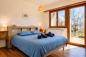 Quarto com cama, mesas de cabeceira, janela e luminária suspensa.