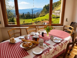Ein Esstisch mit kariertem Tischläufer, Tellern, Besteck und Speisen.