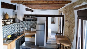 A kitchen with wooden beams, a refrigerator, and a tiled backsplash. - Elegante Apartamento Frente al Puerto de Denia (Dénia)