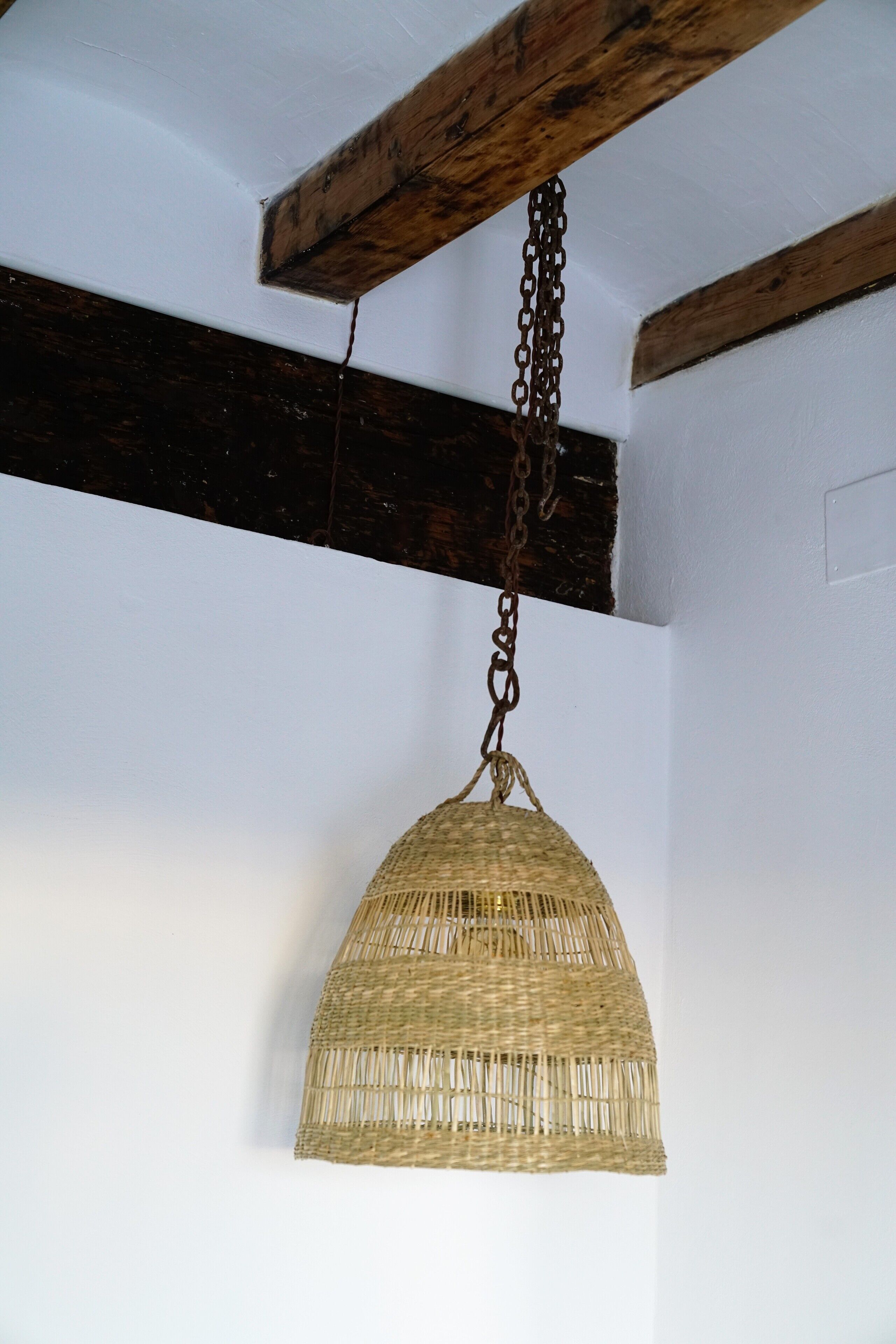 A hanging wicker lamp with a chain.