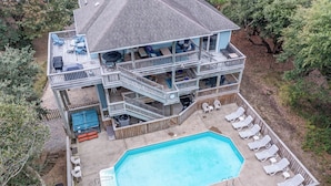 Ein zweistöckiges Haus mit Schwimmbad, Liegestühlen und einer überdachten Terrasse.
