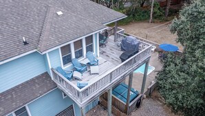 Ein zweistöckiges Haus mit Terrasse, Sitzgelegenheiten im Freien und einem Pool.