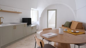 A modern kitchen with a dining area, a flat-screen TV, and a sofa with cushions. - House in the historic center with terrace and panoramic view of the Itria Valley (Locorotondo)