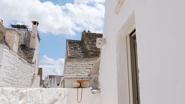 A narrow, white-walled alleyway with a stone floor, leading to a building with a door and a small window. - House in the historic center with terrace and panoramic view of the Itria Valley (Locorotondo)