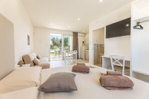 Une chambre d’hôtel moderne équipée d’un lit, d’un coin salon, d’une table à manger et d’un téléviseur.