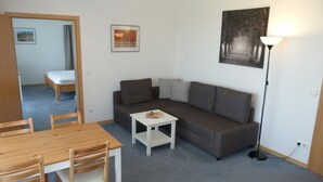 A compact living space with a sofa, a small table, and a dining table with chairs.