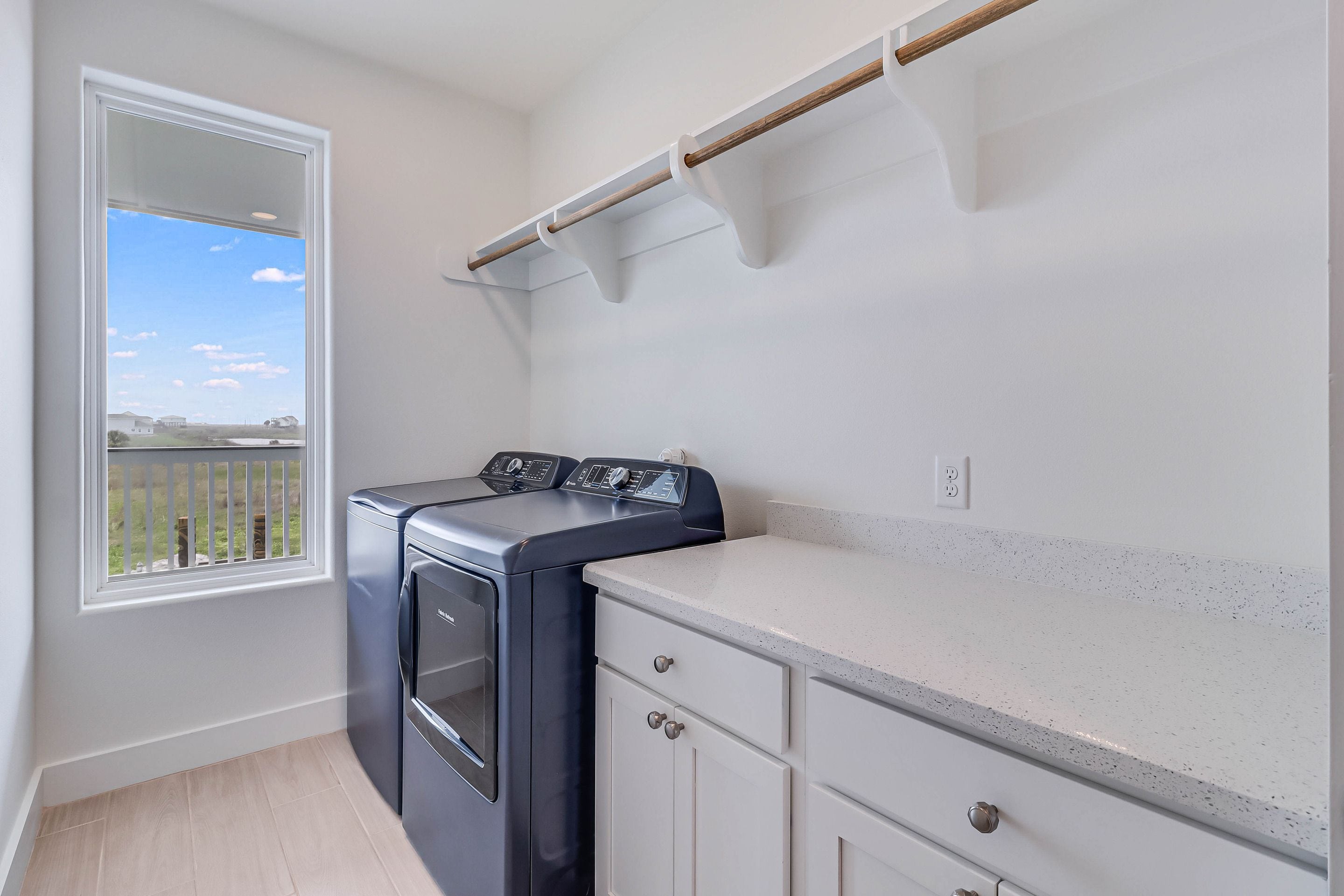 A laundry room with a washer and dryer, a window with a view, and a countertop.