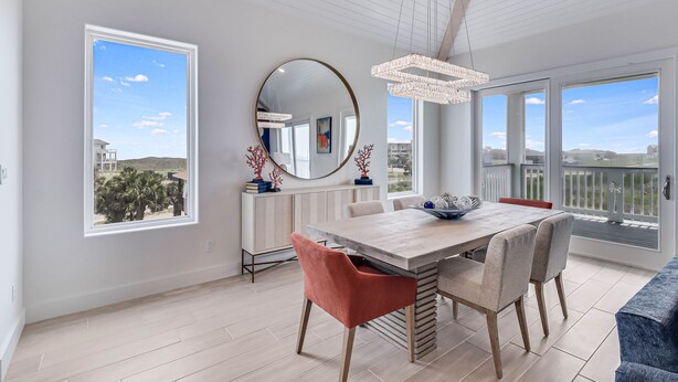 Un coin repas avec une table en bois, des chaises et un grand miroir.
