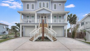 Une maison à deux étages avec un escalier central, une véranda à l’avant et un garage.