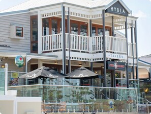 A two-story building with a balcony and outdoor seating area. - Hamptons style two-story 3 bed, 2 bath apartment located at the heart of Binalup (MIDDLETON BEACH)