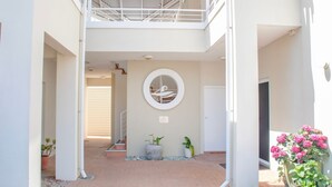 Un edificio con un patio central, un elemento decorativo en forma de pared circular y plantas en macetas.
