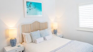 Un dormitorio con una cama, dos mesitas de noche con lámparas, un cuadro en la pared y una ventana con persianas.