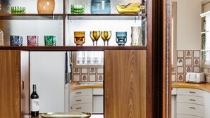 A kitchen with wooden cabinets, a wine bottle, and various kitchenware on shelves. - Harbourview House - coast chic in the CBD (ALBANY)