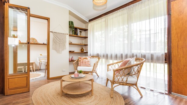 A cozy living room with a round woven rug, wicker chairs, a wooden coffee table, and a bookshelf with decorative items. - Harbourview House - coast chic in the CBD (ALBANY)