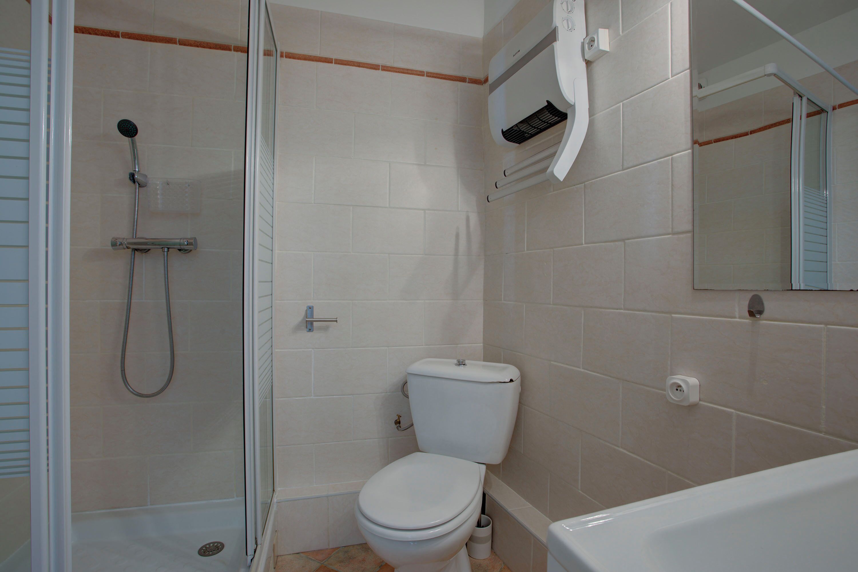 A bathroom with a shower, toilet, and bathtub.
