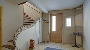 Portaat, joissa on ainutlaatuinen kivikuviointi, puuovi, pieni pöytä, jossa on kori, ja sininen matto laatoitetulla lattialla.