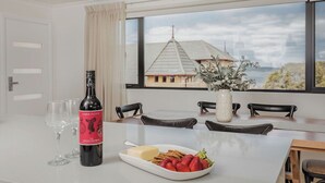 A dining table with a bottle of wine, glasses, and a plate of strawberries and cheese.