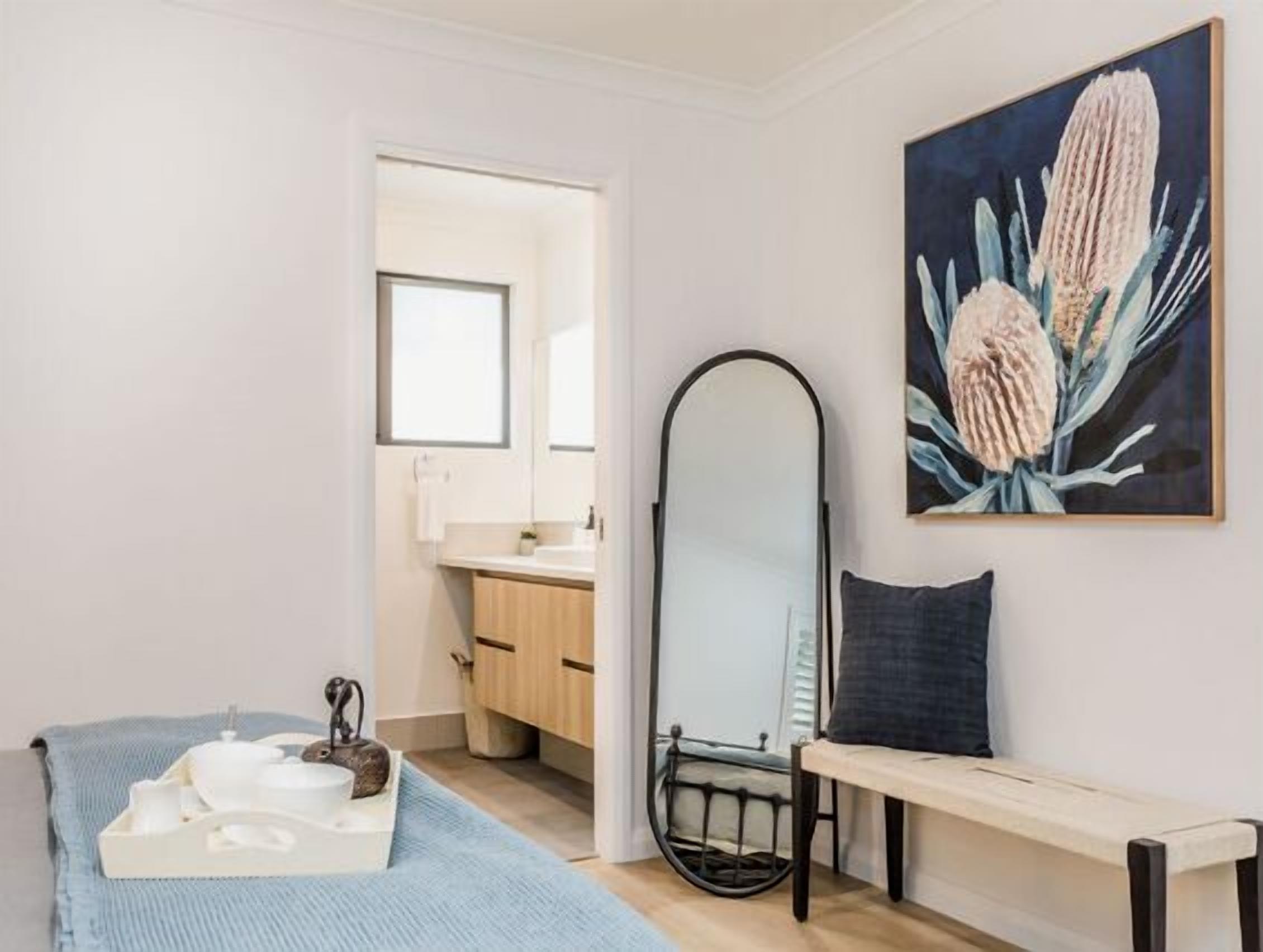 A modern bathroom with a sink, mirror, and a bench.