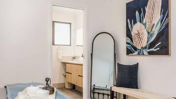 A modern bathroom with a sink, mirror, and a bench.