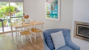 Un comedor con una mesa de madera y sillas blancas, un sofá azul y una chimenea.