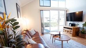 A modern living room with a leather sofa, a wooden coffee table, and a flat-screen TV mounted on the wall. - Your summer Beach Escape is calling (ALBANY)