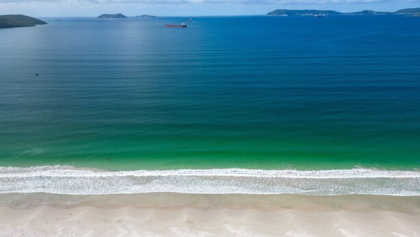 A beach with clear turquoise waters, a sandy shore, and distant islands. - Your summer Beach Escape is calling (ALBANY)
