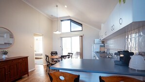A modern kitchen with a central island, wooden chairs, a dining table, and a large window. - Your summer Beach Escape is calling (ALBANY)