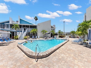 A swimming pool with lounge chairs and a building with a blue exterior.