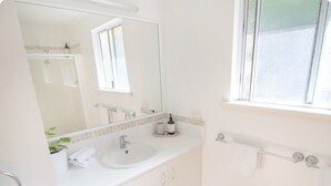 A clean, white bathroom with a sink, mirror, and window. - Cute upstairs 2 bedroom apartment perfect for short stays while visiting Albany (MIRA MAR)