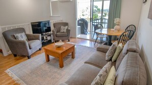 A living room with a sofa, armchair, coffee table, and a TV. - Cute upstairs 2 bedroom apartment perfect for short stays while visiting Albany (MIRA MAR)