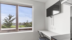 A modern kitchen with a large window, a flat-screen TV mounted above the counter, and a chair in the corner. - Executive Apartment (London)