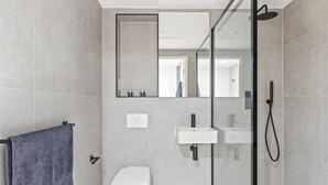 A modern bathroom with a glass shower enclosure, a white toilet, and a sink. - Executive Apartment (London)