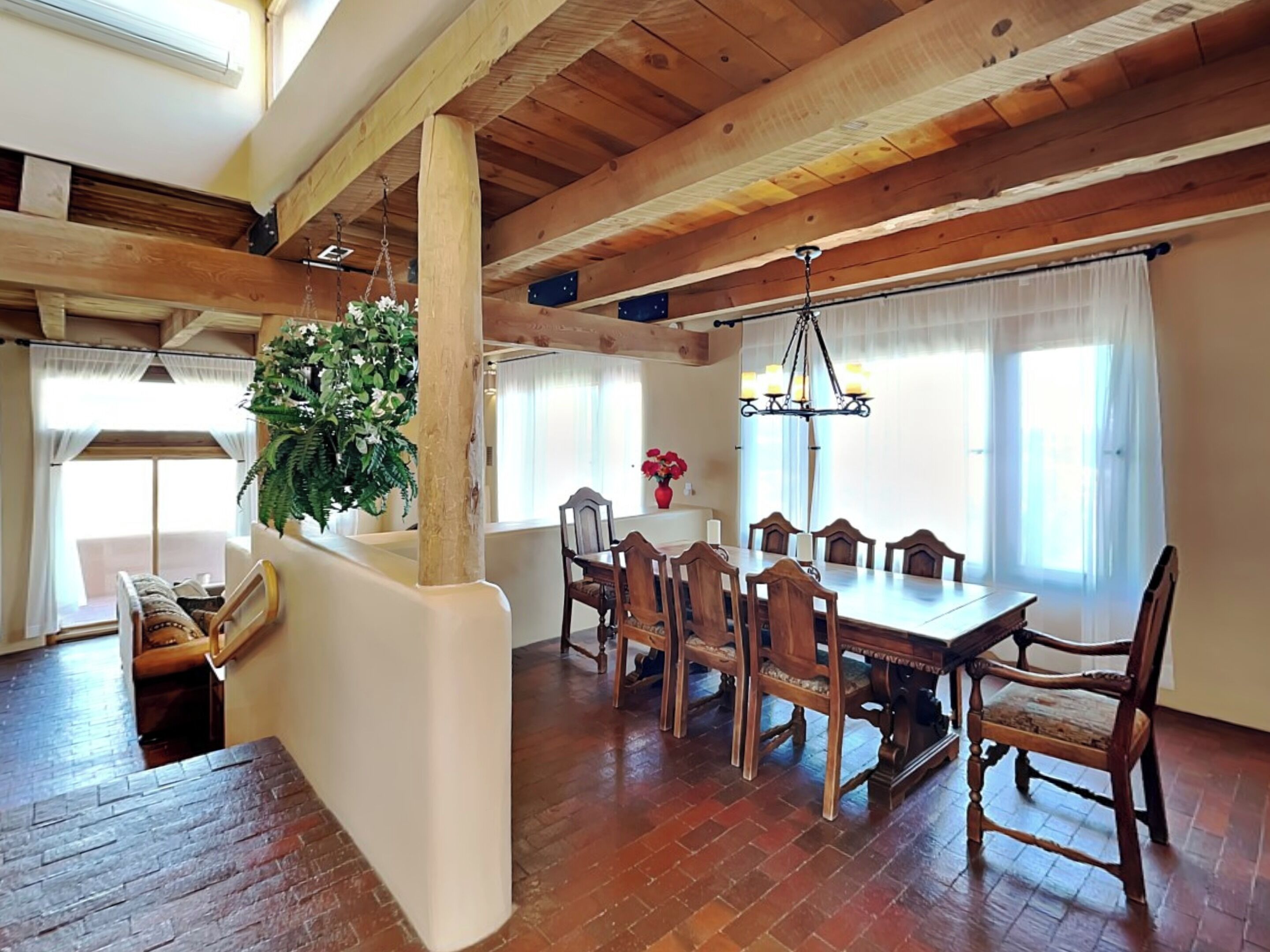 Zona pranzo con tavolo e sedie in legno, una pianta pensile e un lampadario.