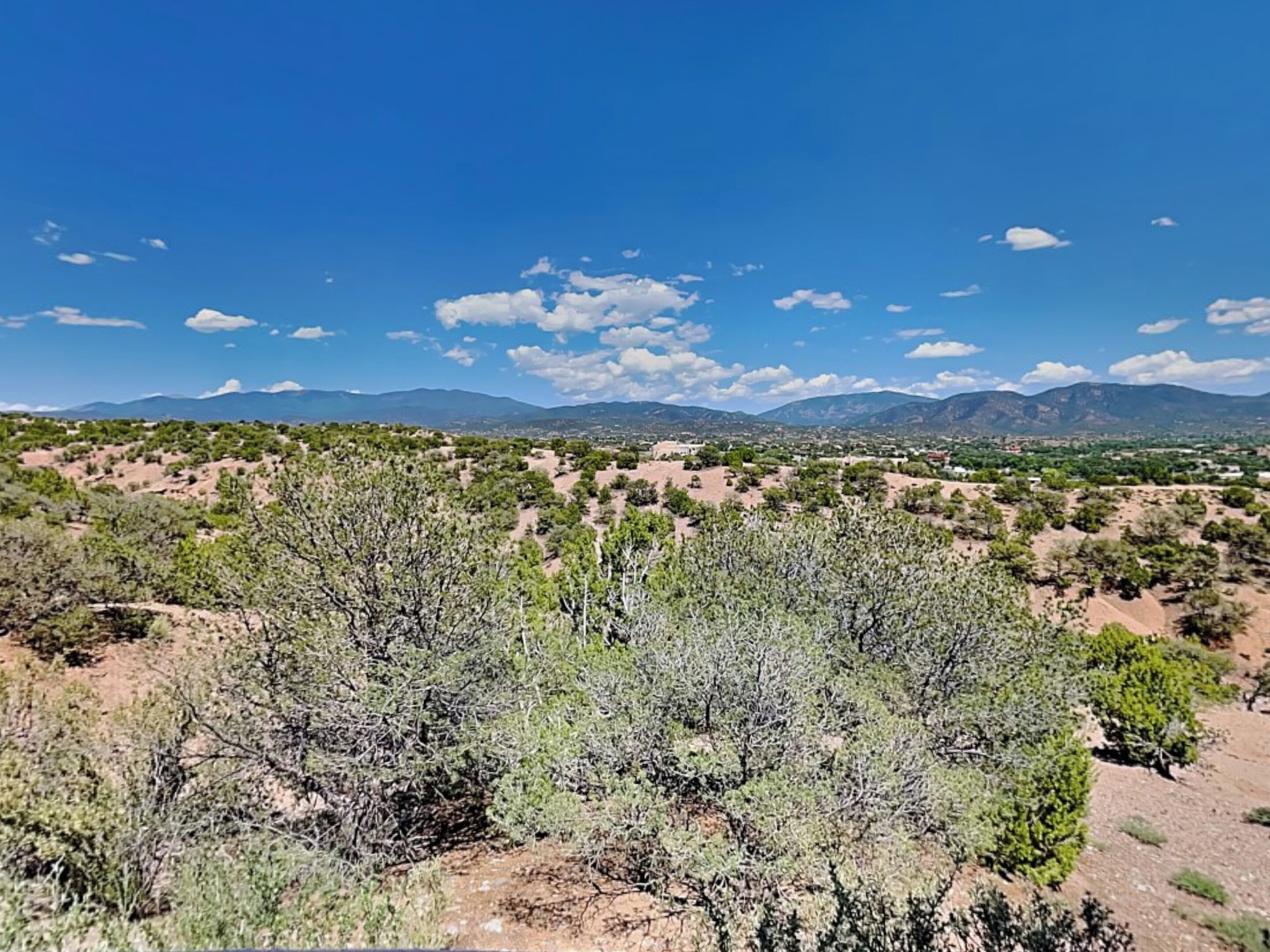 A desert landscape with sparse vegetation and distant mountains under a clear sky.