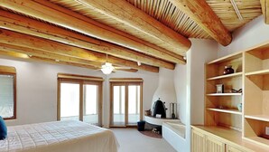 Un dormitorio con cama, ventilador de techo, chimenea y estanterías empotradas.