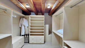 Un vestidor con vigas de madera, una percha y estantes abiertos.