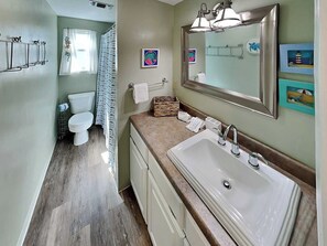 A bathroom with a large sink, a mirror, and a shower area.