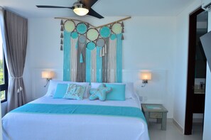 A bedroom with a bed, two bedside lamps, a ceiling fan, and a wall hanging. - Heart designed Apartment, Ocean and Lagoon view, large terrace  (Cancún)