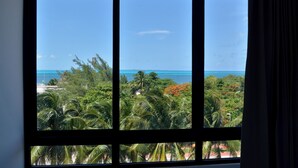 A large window with a view of a tropical landscape, including palm trees and a clear blue sky. - Heart designed Apartment, Ocean and Lagoon view, large terrace  (Cancún)