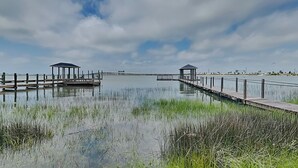 A calm waterfront with wooden walkways and two gazebos. - Dock of the Bay by Ryson Vacation Rentals (Galveston)