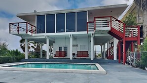 A modern building with a pool, red railings, and a sign that reads "House". - Dock of the Bay by Ryson Vacation Rentals (Galveston)