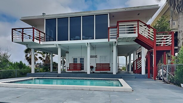 A modern building with a pool, red railings, and a sign that reads "House". - Dock of the Bay by Ryson Vacation Rentals (Galveston)