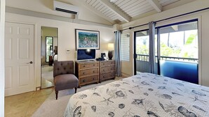 A bedroom with a large bed, a television, a dresser, a chair, and a balcony with a view. - Wailea Ekolu Village 1406 by Maui Rental Group (Kihei)