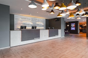 A hotel reception area with a modern design, featuring a reception desk, multiple pendant lights, and a large wall with motivational phrases. - Premier Inn Karlsruhe City Am Wasserturm (Karlsruhe)