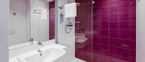 Un baño moderno con ducha envuelta en vidrio, un lavabo blanco y un espejo de tocador.