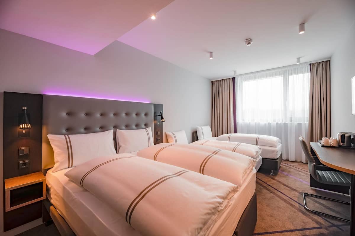 A hotel room with a large bed, a desk, and a window with curtains.