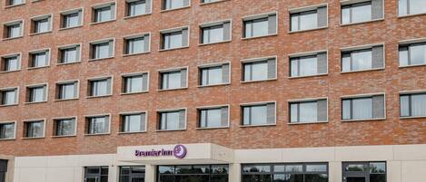 Un edificio de varios pisos de ladrillo con el letrero 'Premier Inn', grandes ventanales y una entrada a nivel de calle.