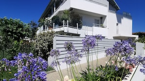 Ein modernes, zweistöckiges Haus mit weißer Fassade und einem Balkon.