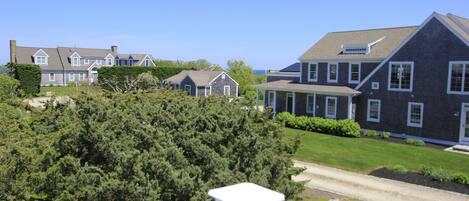 A residential area with multiple houses, a well-maintained lawn, and a clear sky.