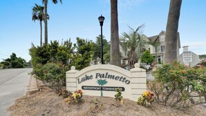 Schild für Lake Palmetto Waterfront Townhomes mit einer Straßenlaterne und Palmen im Hintergrund.